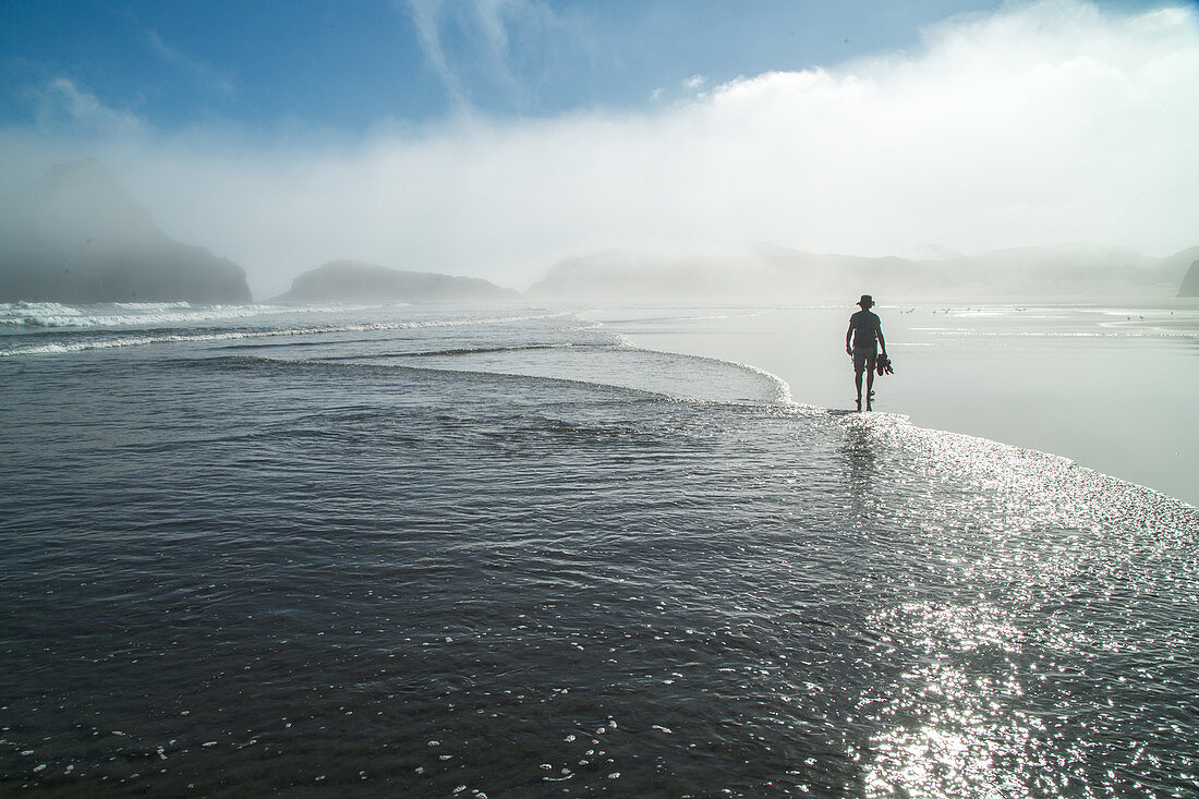 Wharariki Strand, Person mit Sandalen in der Hand, läuft durch das flache Wasser, Seenebel, Küstennebel, morgens, weiter Sandstrand, Natur, Landschaft, mystisch, Natur, Meer, Wasser, Westküste, Südinsel, Neuseeland