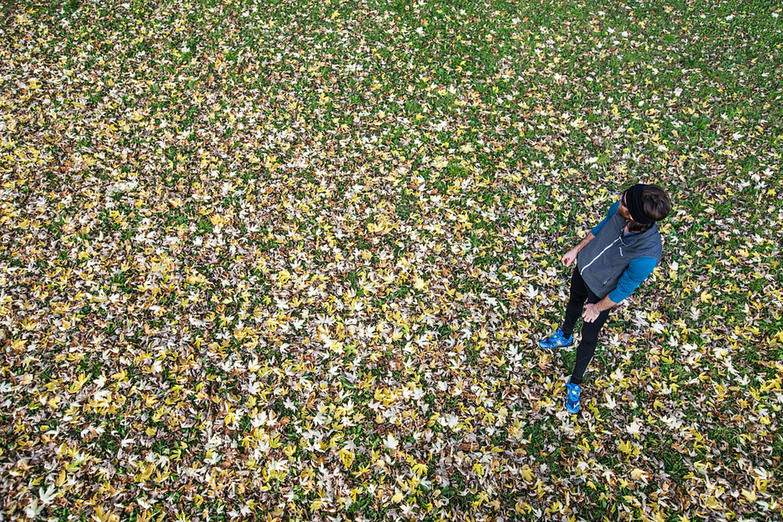 Junger Mann steht auf einer mit Blättern bedeckten Wiese, Allgäu, Bayern, Deutschland