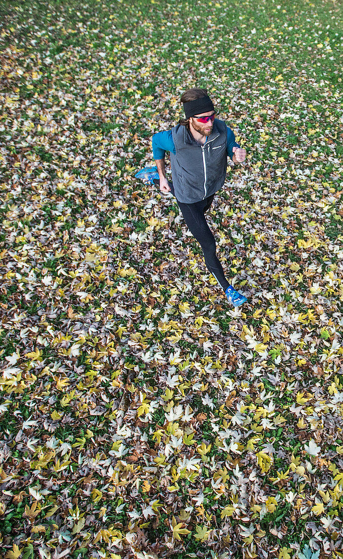 Young man running over a meadow covered in leaves, Allgaeu, Bavaria, Germany