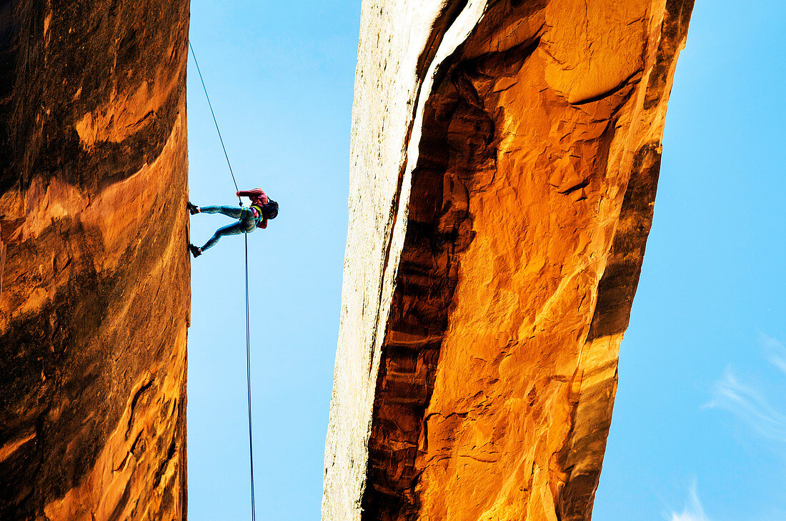 Rock climber using rope on arch