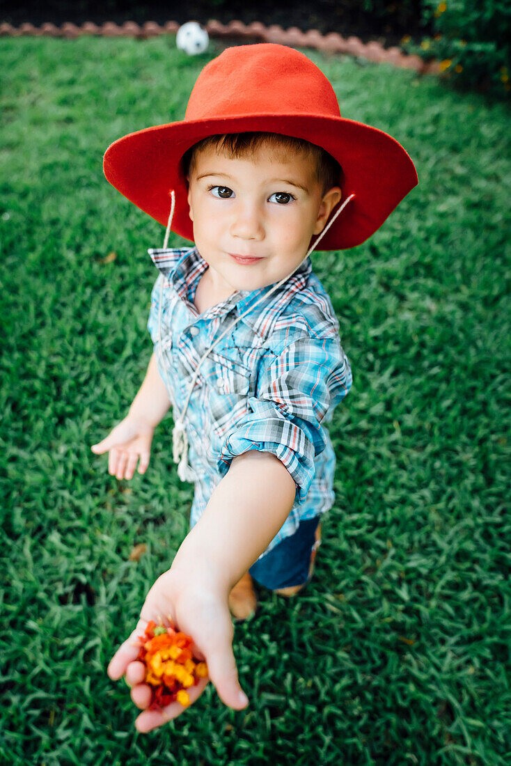 Caucasian boy wearing cowboy hat showing flowers in hand