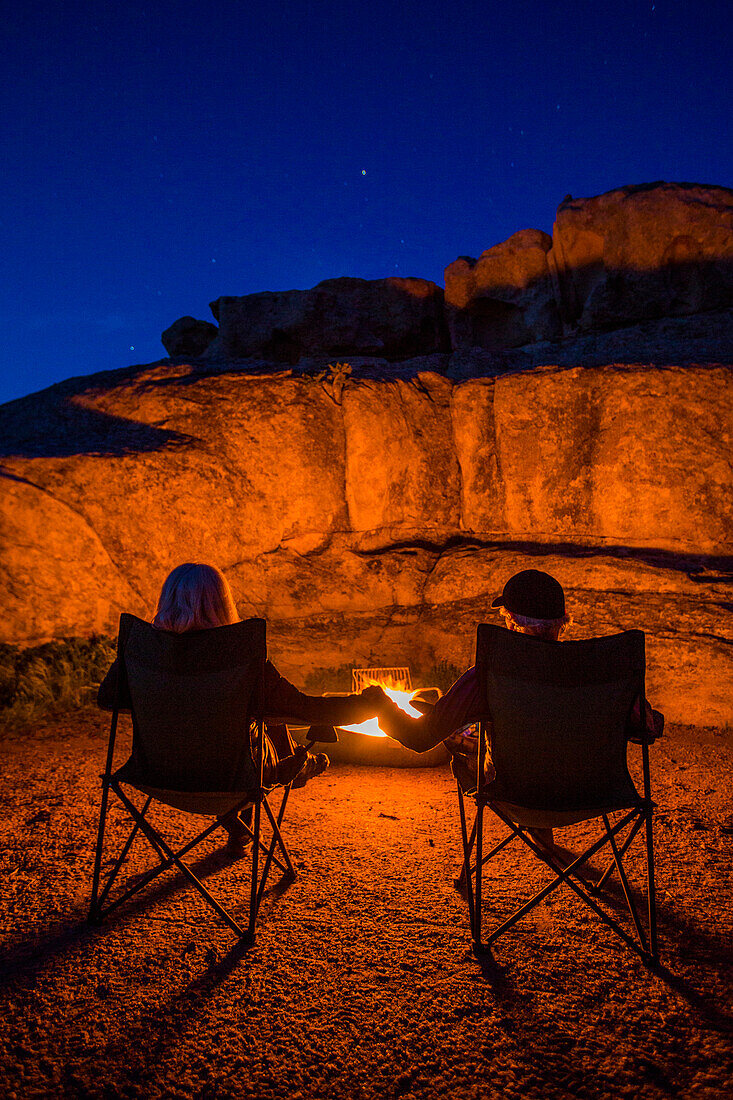 Caucasian couple holding hands near campfire at night