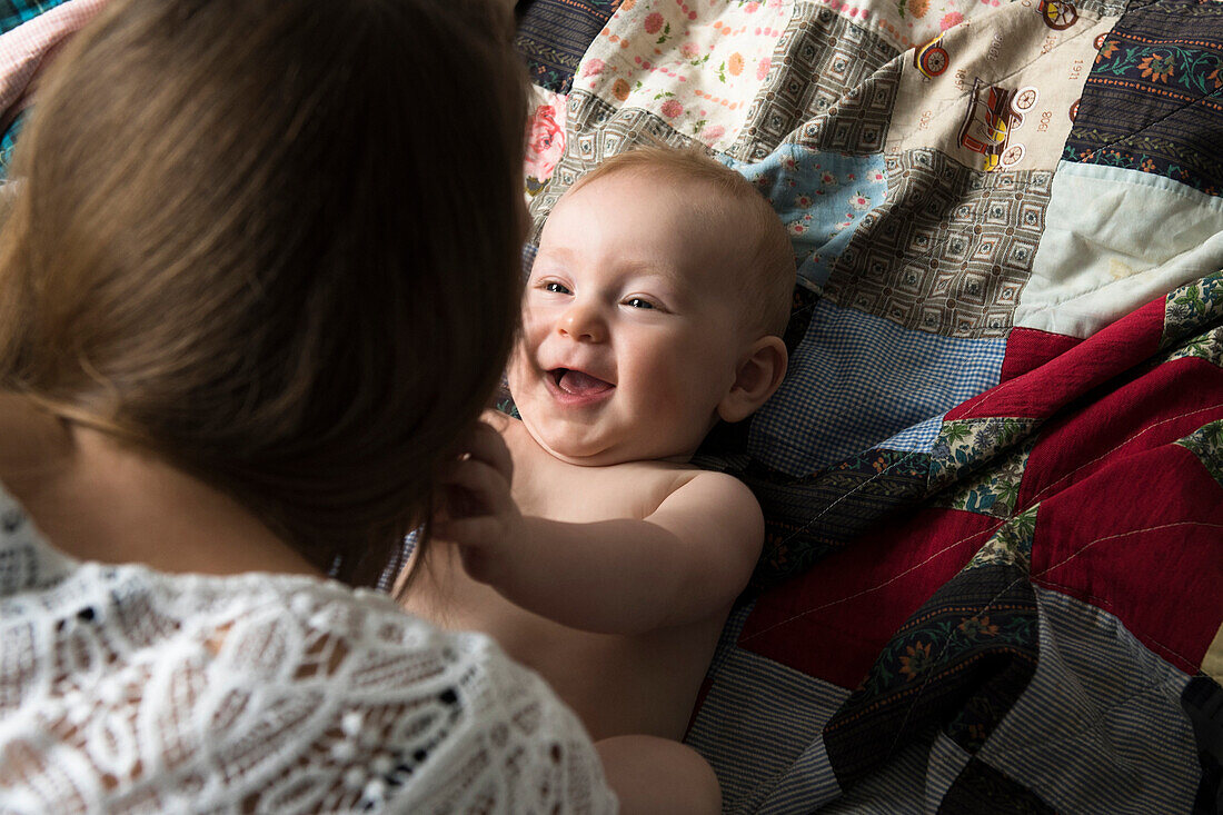 Caucasian mother playing with baby son on blanket