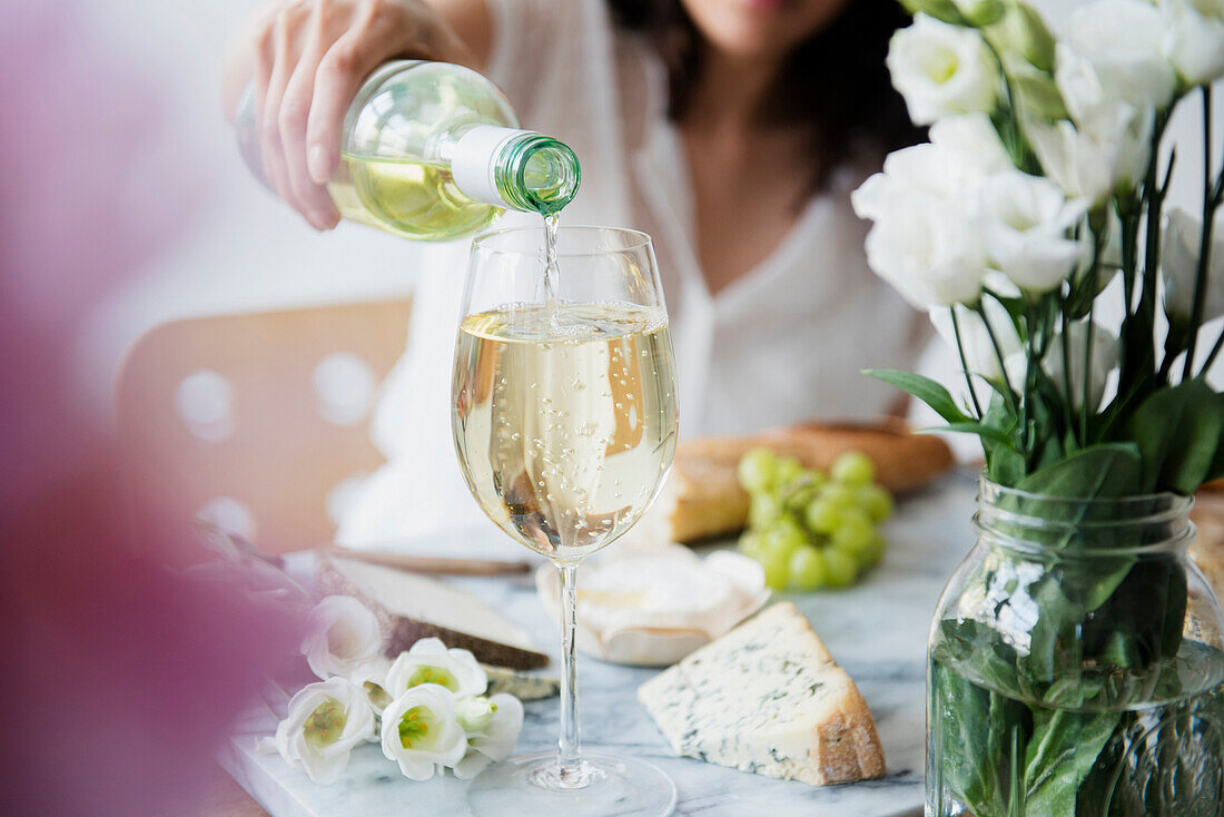 Hispanic woman pouring wine at table