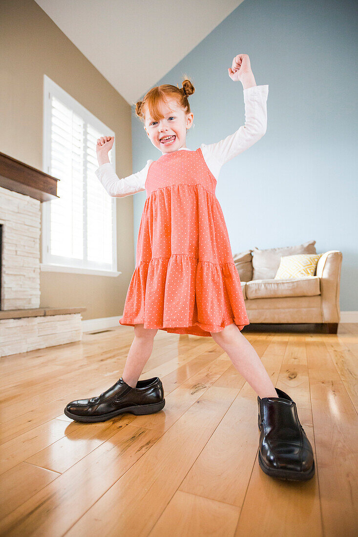 Caucasian girl wearing shoes of father in living room