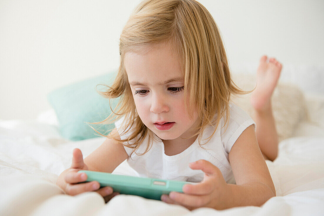 Caucasian girl using cell phone on bed