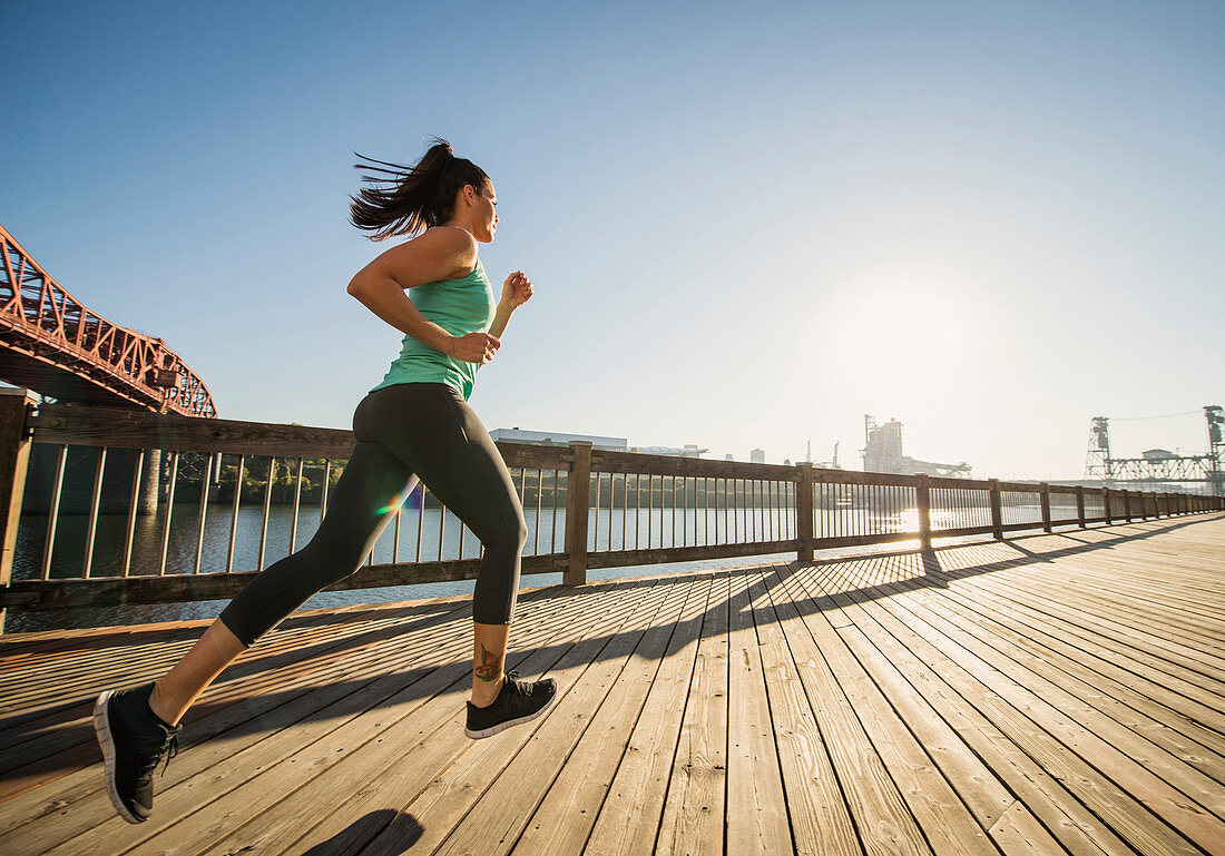 Caucasian woman jogging on urban waterfront