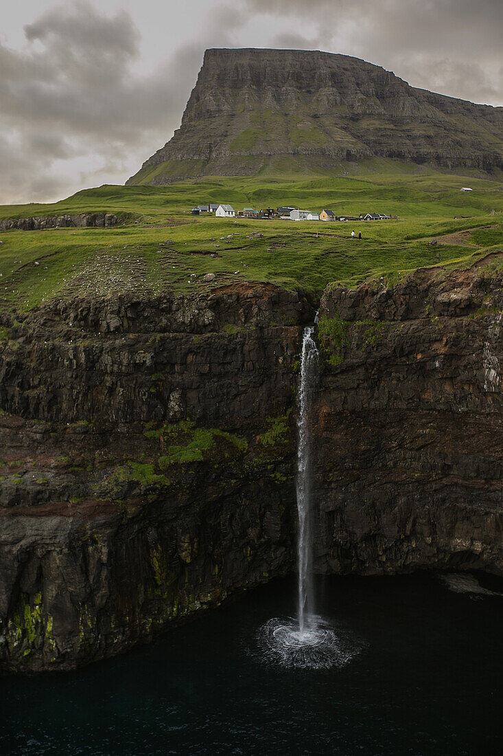 Wasserfall fließt von einer hohen Klippe ins Meer, Färöer Inseln