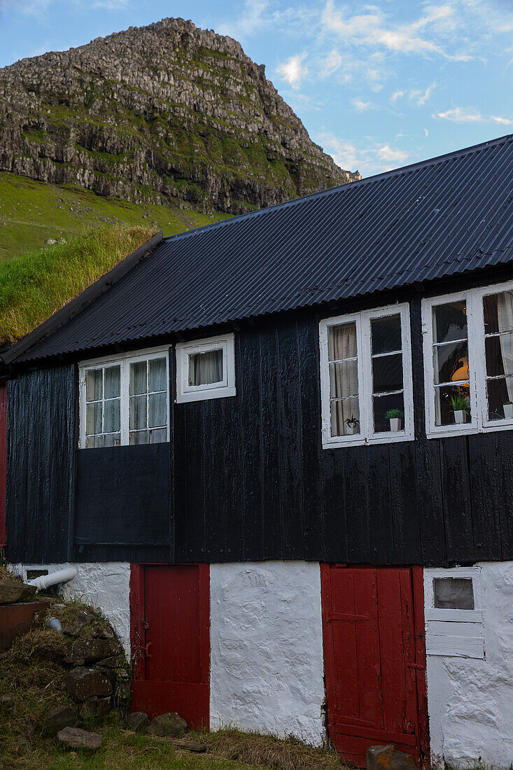 Altes Haus in der Nähe eines grün bewachsenen Berges, Färöer Inseln