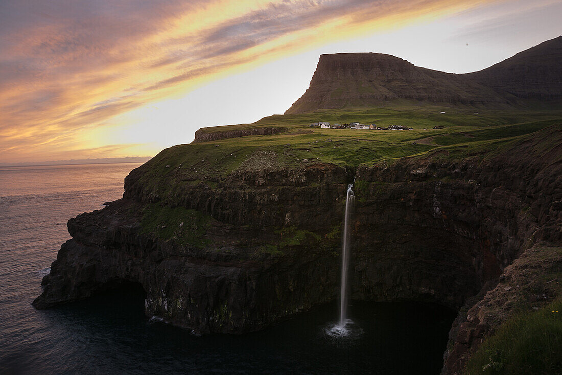 Waterfall flowing from a high cliff into the sea, Faeroe Islands