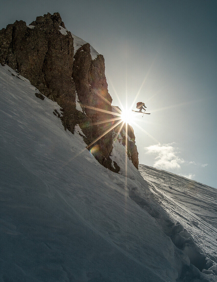 Young male skier jumping down a cliff in the mountains, Gudauri, Mtskheta-Mtianeti, Georgia