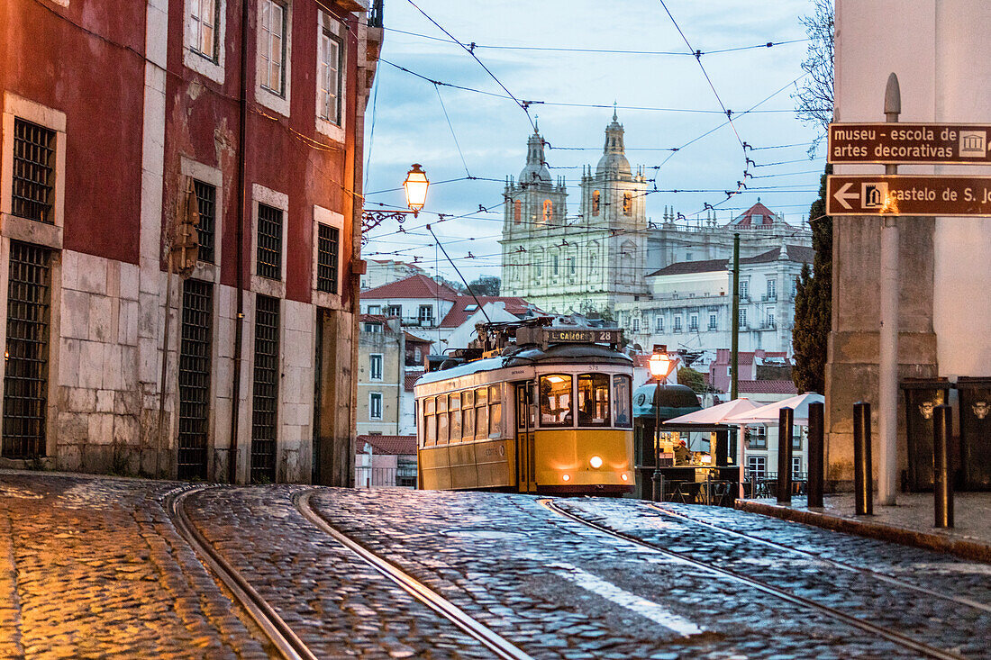 Romantische Atmosphäre in den alten Straßen von Alfama mit der Burg im Hintergrund und Straßenbahn Nr. 28, Lissabon, Portugal, Europa
