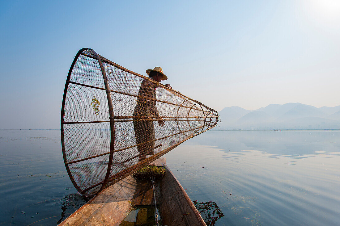 A basket fisherman on Inle Lake prepares to plunge his cone shaped net, Shan State, Myanmar (Burma), Asia
