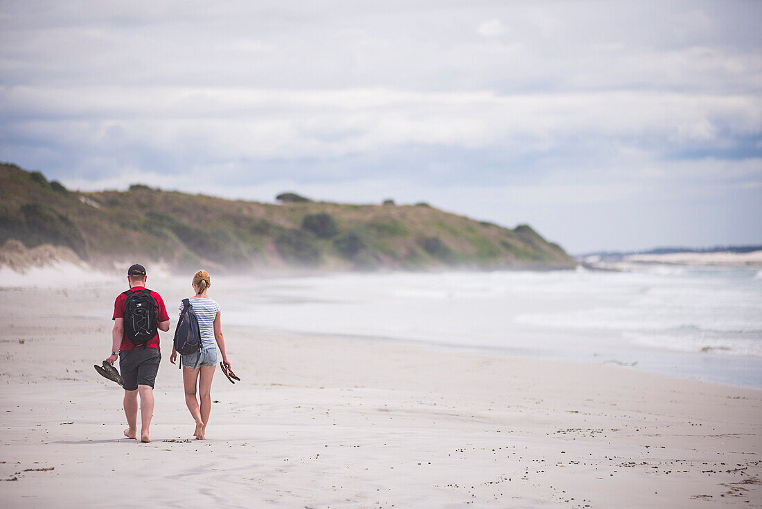 Touristen zu Fuß auf Rarawa Beach, ein beliebter und schöner weißer Sandstrand in Northland Region, Nordinsel, Neuseeland, Pazifik