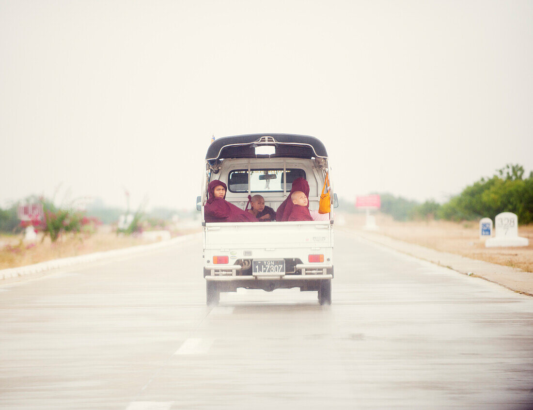 Buddhistische Mönche reisen in den Rücken einer Abholung auf einer modernen Autobahn, Myanmar (Burma), Asien