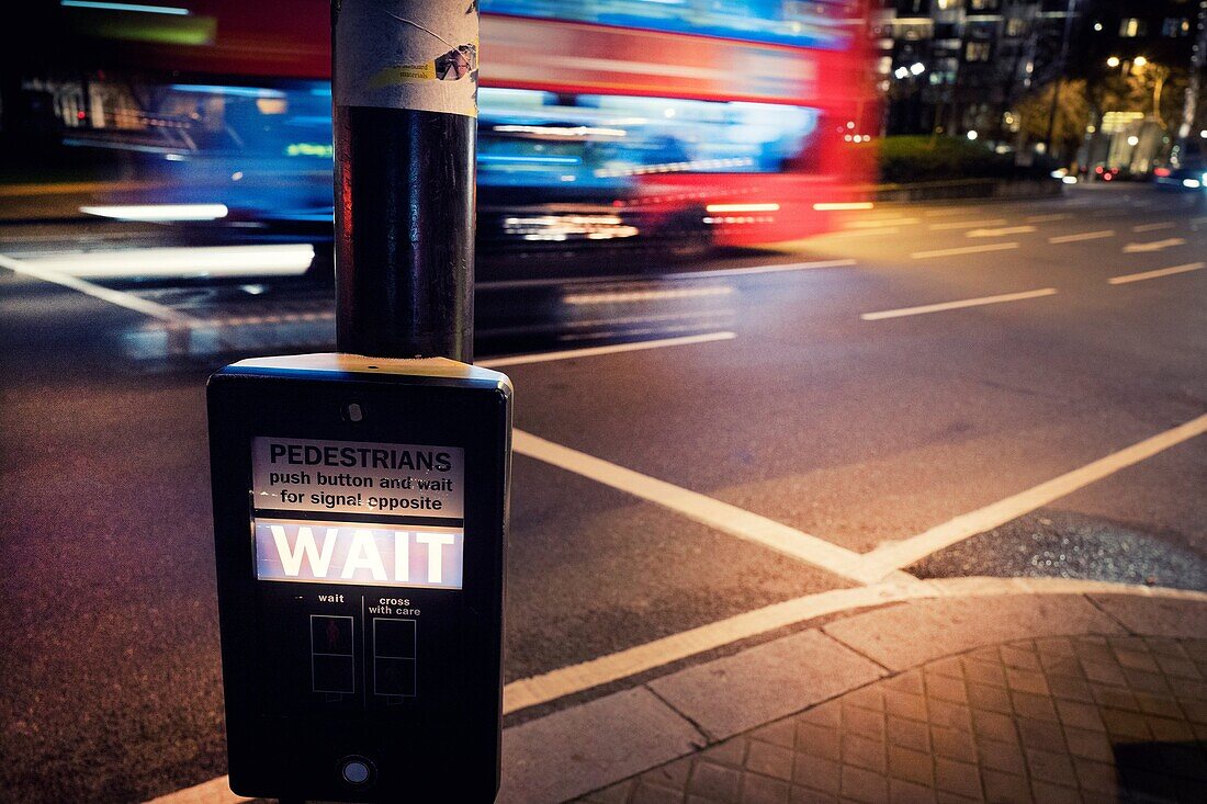 Nahaufnahme von einem Post mit 'WAIT' Signal in einem Fußgängerüberweg, mit Bus in verschwommene Bewegung auf Hintergrund. Herzog von Wellington Place, London, England