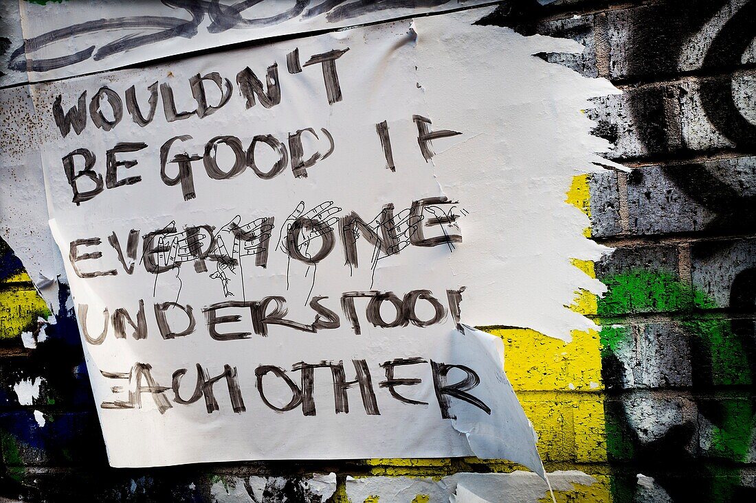 Close-up von Mauer mit Graffiti und Zeichen lesen 'Wäre nicht gut, wenn jeder einander verstanden'. East End, London, England