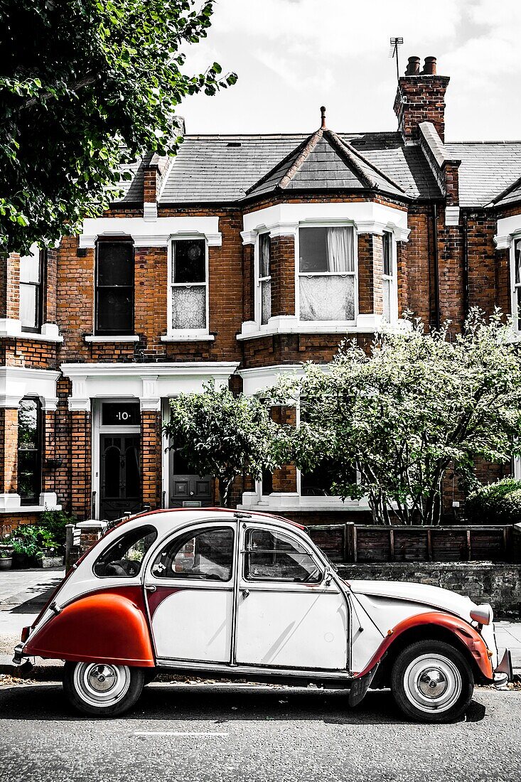 Retro car parked on roadside in sunlight. Vintage cottage on background.