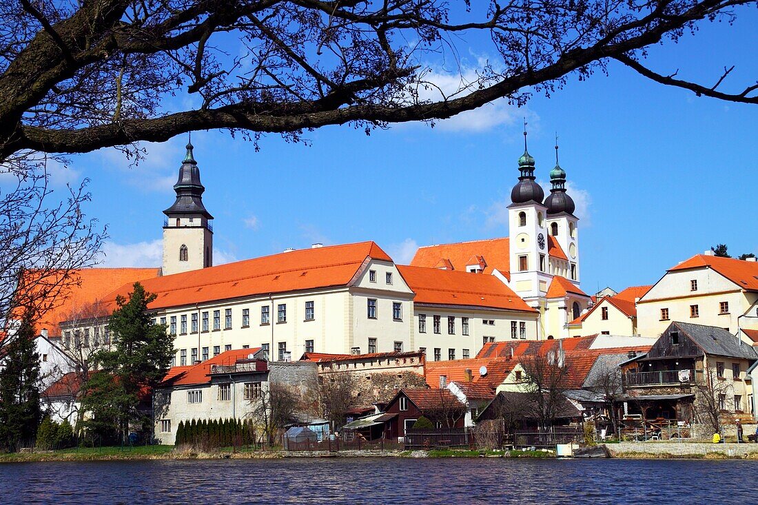 Holy Name of Jesus church and houses by the shore of the Ulicky pond Telc Czech Republic.