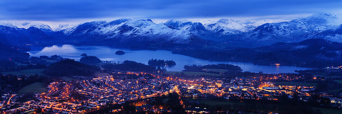 Looking over Keswick to Derwent Water and the snow capped mountains in the Lake District National Park at dusk, Cumbria, England, United Kingdom, Europe