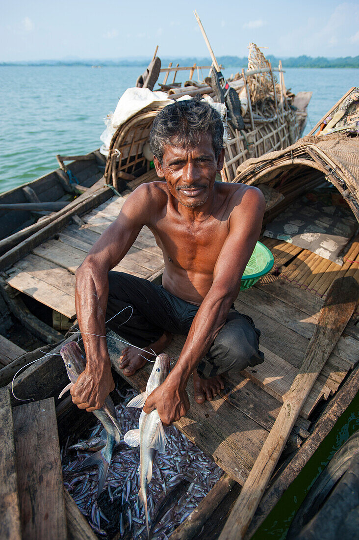 A fisherman holds a fresh catch on Kaptai Lake in the Chittagong Hill Tracts, Bangladesh, Asia
