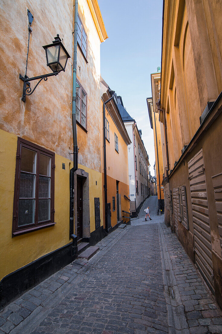 A pedestrian walks the streets of Stockholm's colorful and historic Gamla Stan district, Stockholm, Sweden, Scandinavia, Europe