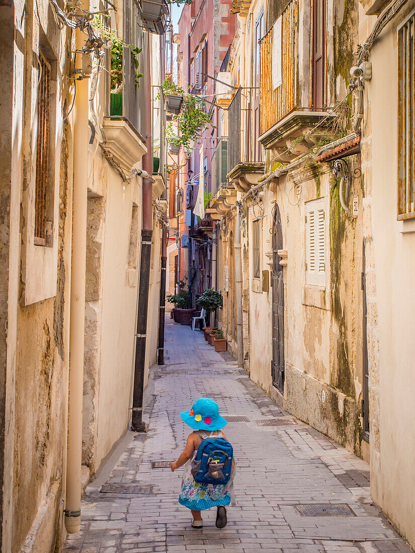 Little girl heading down a narrow Sicilian lane, Syracuse, Sicily, Italy, Europe