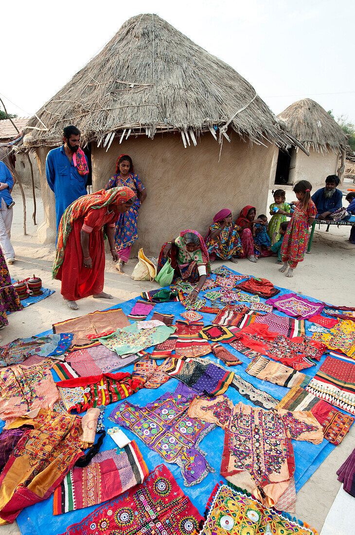 Pathan Dorf Frauen zeigen ihre traditionellen Stickereien vor Schlamm und strohgedeckten Stammeshäuser, Jarawali, Kutch, Gujarat, Indien, Asien