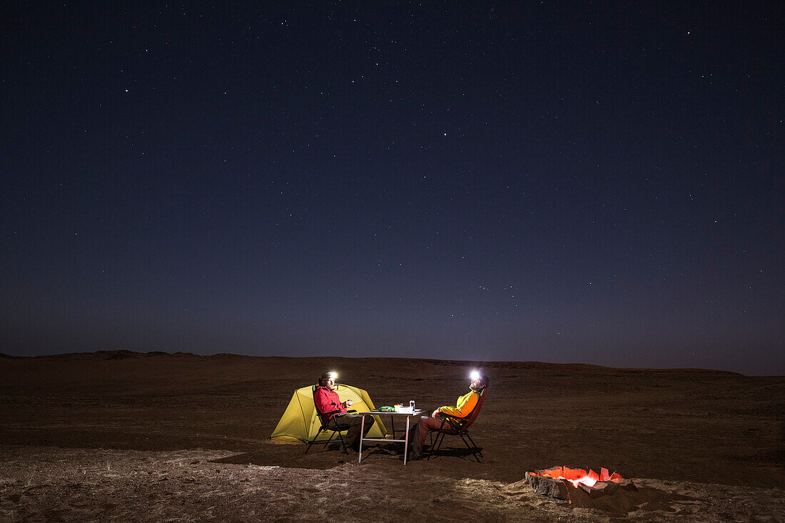 Zwei Männer kampieren unter dem Sternenhimmel in der Steppe des Damaraland, Kunene, Namibia