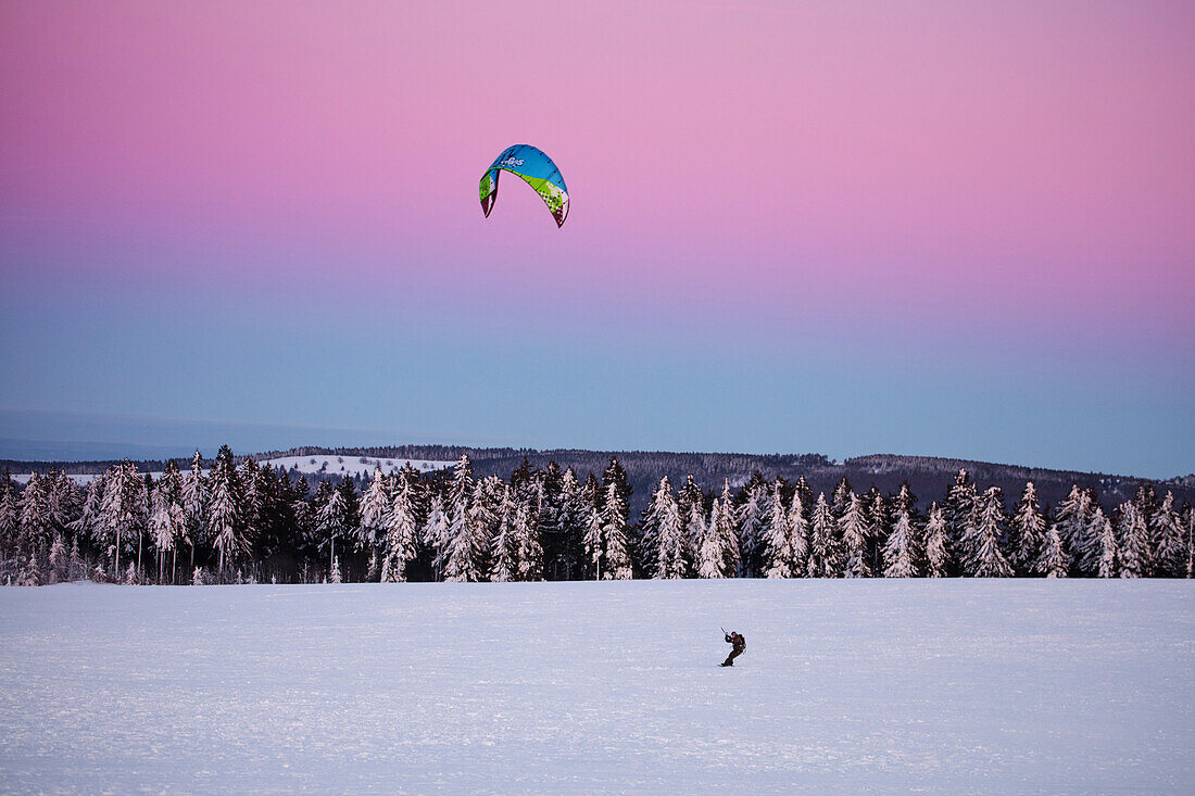 Snowkiting on Wasserkuppe mountain in winter at dusk, near Poppenhausen, Rhoen, Hesse, Germany