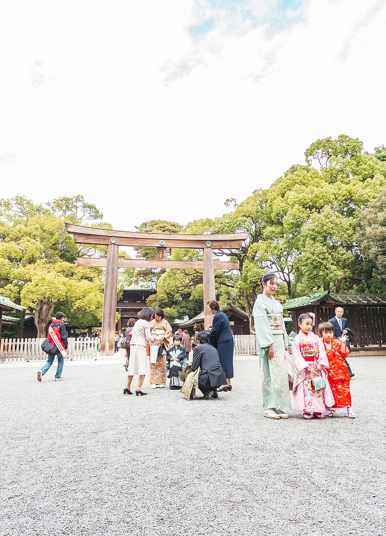 Japanerin mit Töchtern vor hölzernem Tor am Meiji Schrein, Shibuya, Tokio, Japan