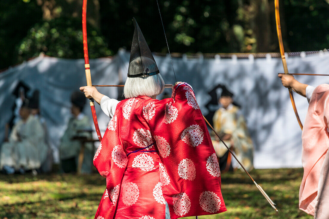 Bogenschützin im roter Tracht während des Herbst Grand Festivals am Meiji Schrein, Shibuya, Tokio, Japan