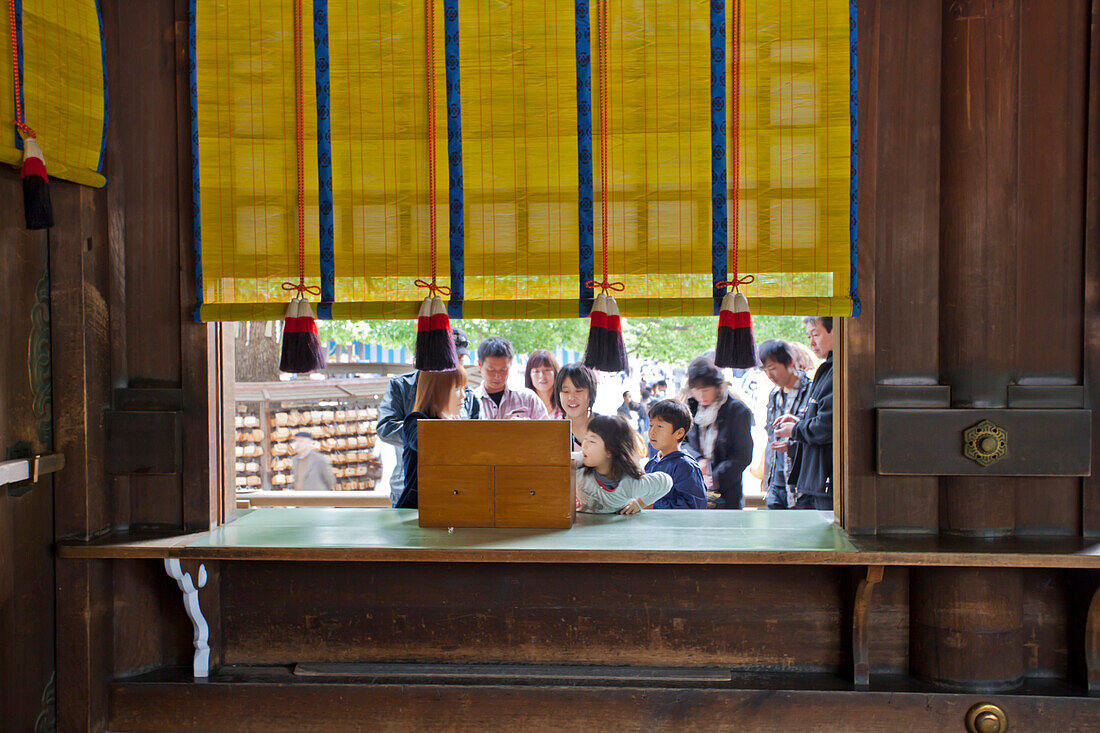 Japanische Familie beim Ziehen eines Glückslos am Meiji Schrein, Shibuya, Tokio, Japan