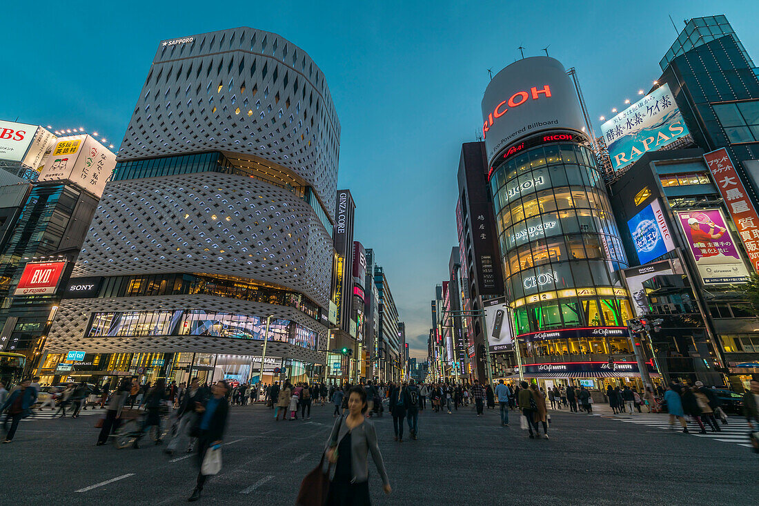 Kreuzung mit Fußgängern am Ginza Place und Ricoh Imaging Square in der Ginza während der blauen Stunde, Chuo-ku, Tokio, Japan