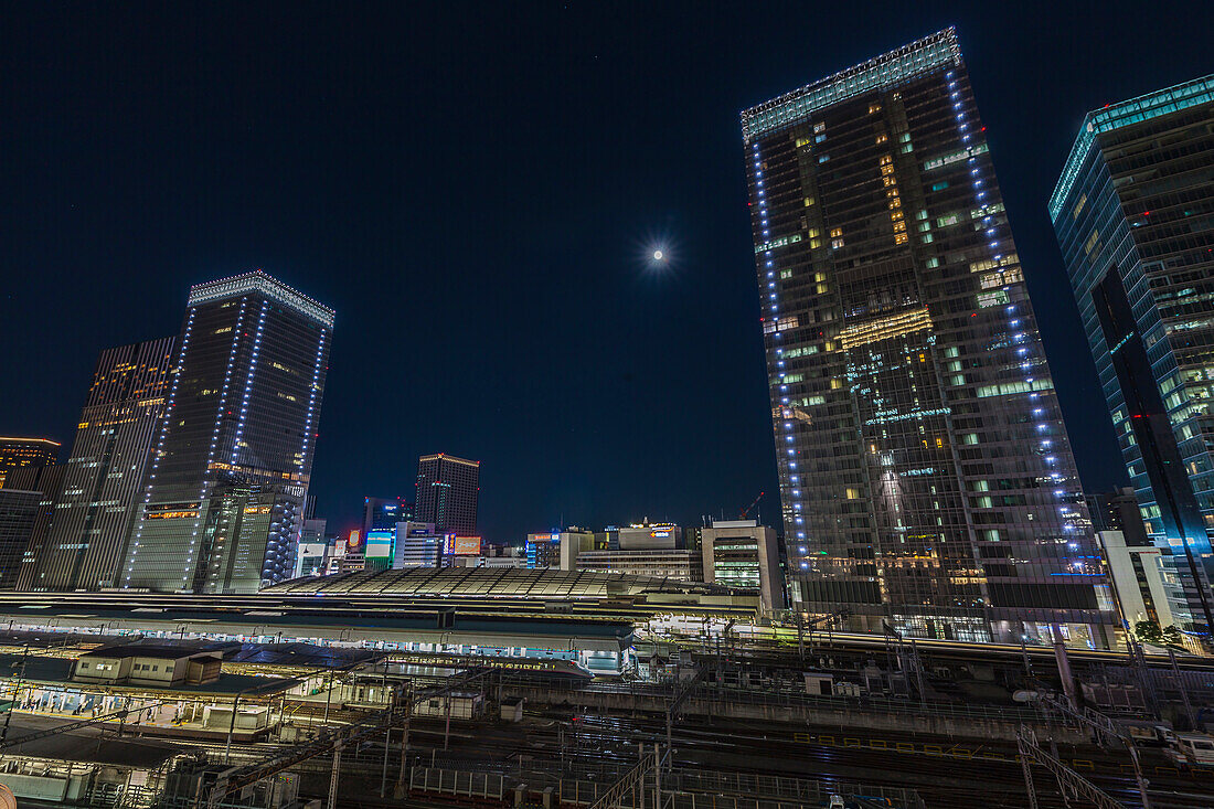Train tracks of Tokyo Station with skyscrapers during full moon, Chuo-ku, Tokyo, Japan