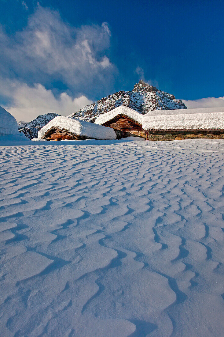 The wind shapes the snow that fell between the traditional huts of the Alpe Prabello. Valmalenco. Valtellina Lombardy. Italy Europe.