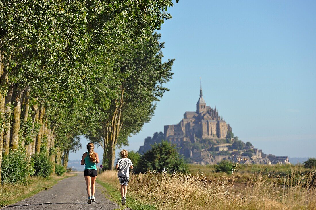 Jogger auf einem Weg im Polder der Bucht von Mont-Saint-Michel, Departement Manche, Region Normandie, Frankreich, Europa.