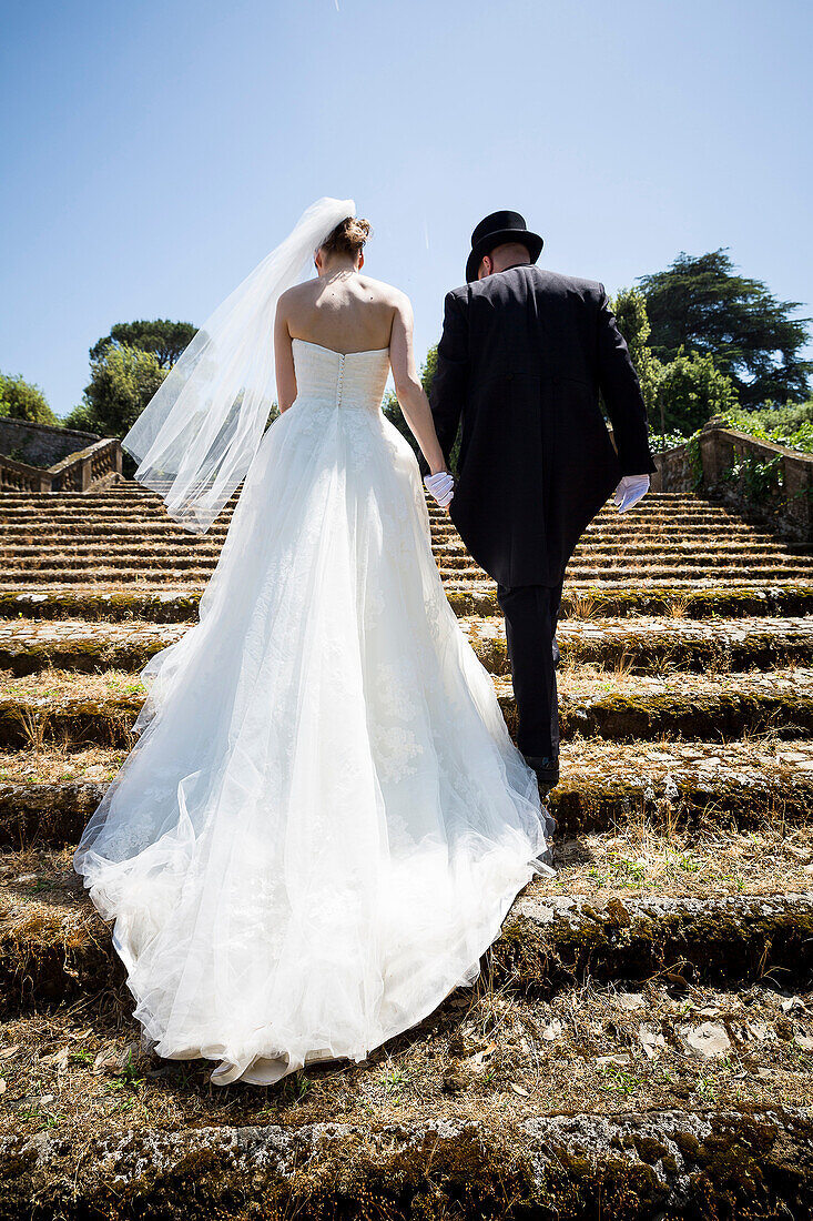 Bride, groom, matrimony, matrimonial, getting, married, just married, together, walk, walking, up, stairs, staircase, Italy, Italian, gown, wedding day, newlyweds, lifestyle, bridal