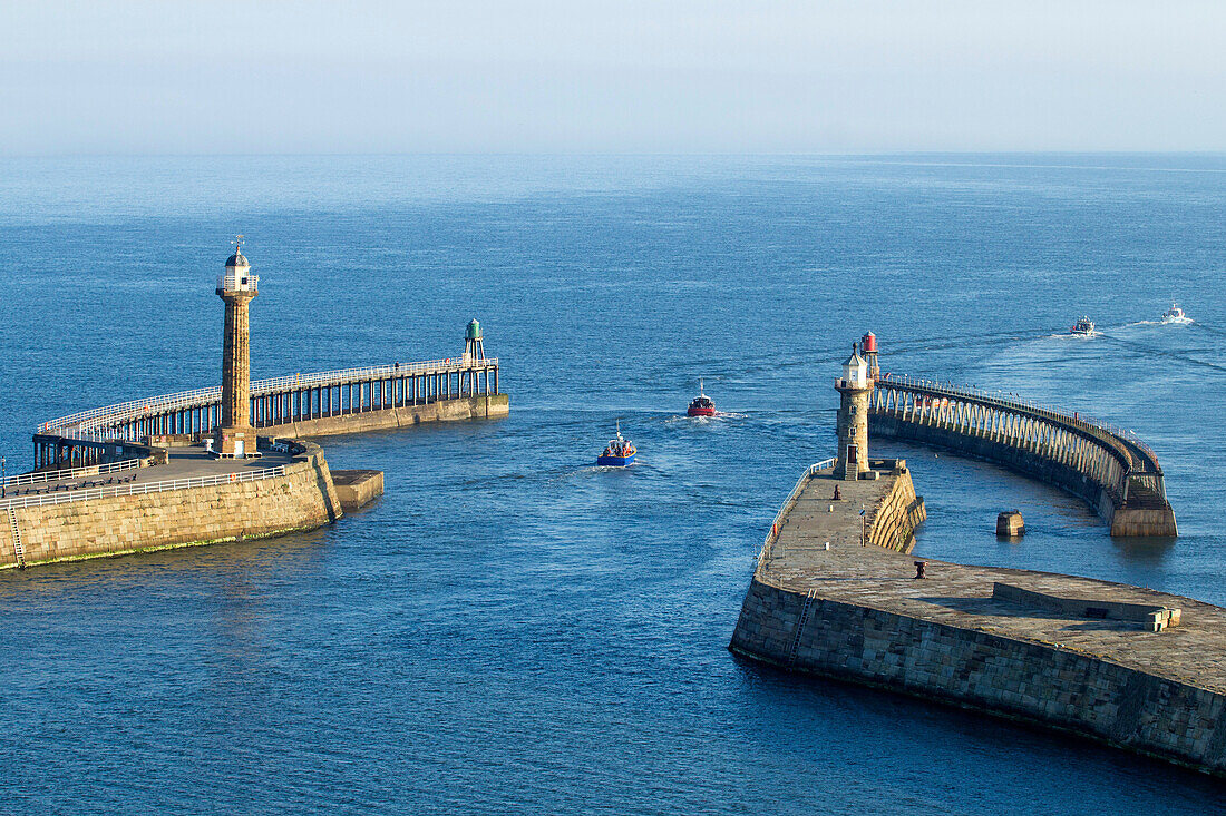 Tourist boat entering harbour between piers. Whitby, North Yorkshire, England, United Kingdom.