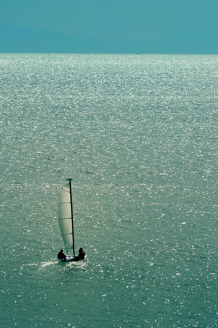 Small sail boat heading to the sea away from the shore.