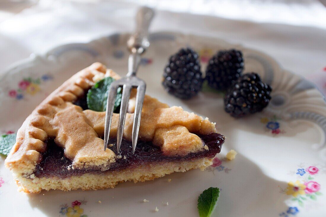 Presentation of a slice of tart with blackberry jam.