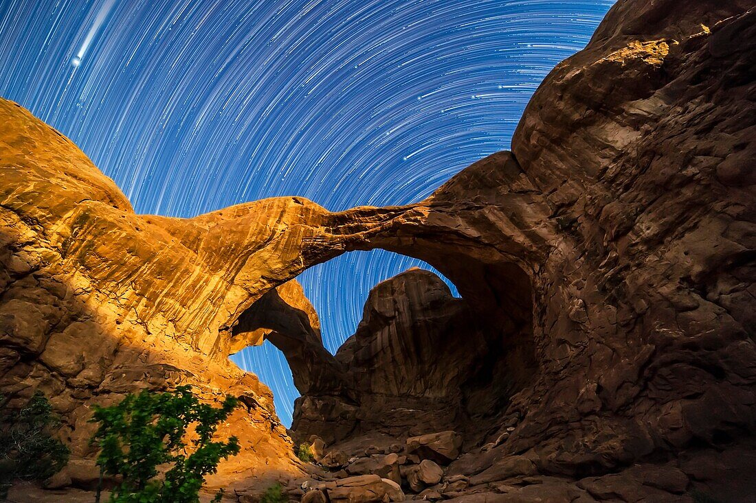Circumpolar star trails spinning behind Double Arch at Arches National Park, Utah, as the waning gibbous Moon lights the arches toward the end of the sequence. The Big Dipper is streakng into frame at top right from behind the butte at right, while Jupite
