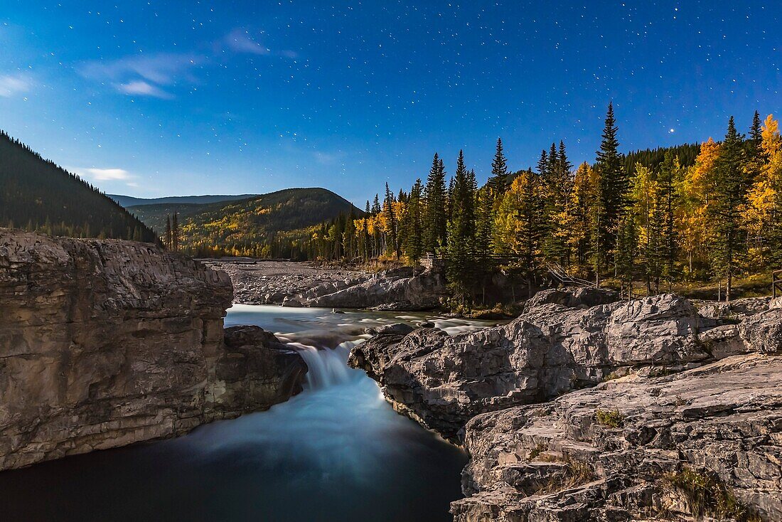Stars over Elbow Falls in the Kananaskis area of southern Alberta, shot under the light of the gibbous Moon on the last night of summer, September 22, 2015. The aspens were in full fall foliage on a very clear, mild night.This is a stack of 6 images, one 
