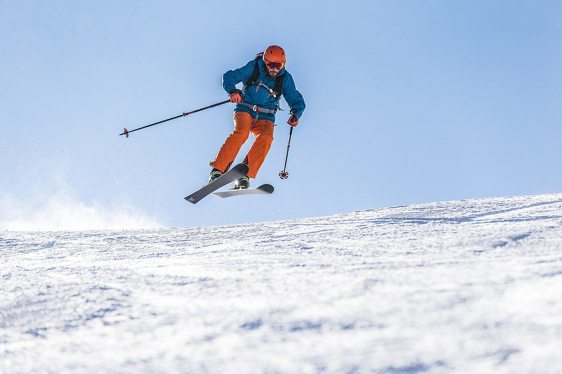 Junger Skifahrer springt über eine Piste, Kaprun, Salzburg, Österreich