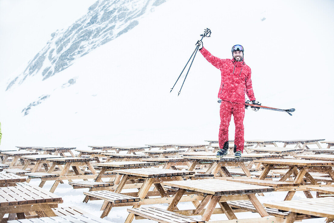 Junger Skifahrer steht auf dem Tisch eines Restaurants in den Bergen, Kaprun, Salzburg, Österreich