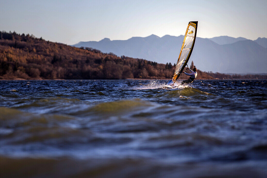 Young man windsurfing while sunset, Ammersee, Bavaria, Germany