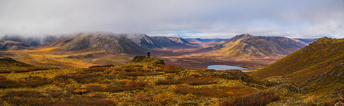 'Man standing on a lookout overlooking the Blackstone Valley along the Dempster Highway; Yukon, Canada'