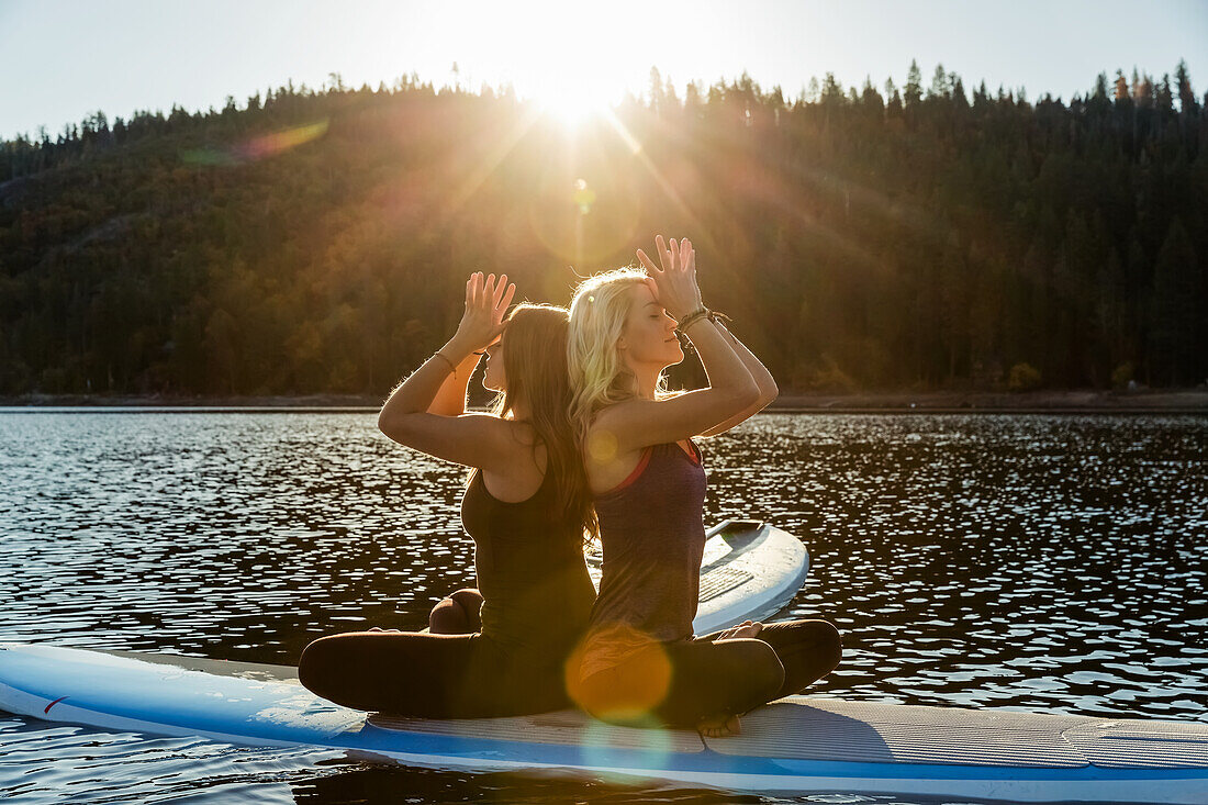 'Fitness models doing yoga on a paddleboard on Pinecrest Lake; California, United States of America'