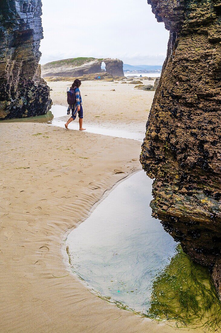 Female solo traveler at Beach of the Cathedrals Natural Monument at Ribadeo municipality, Lugo province, Galicia, Spain, Europe.