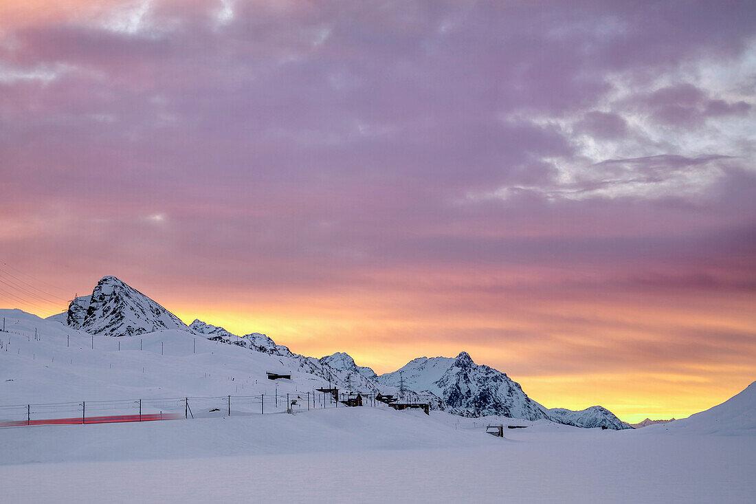 Pink clouds and snow frame the Bernina Express train at dawn, Bernina Pass, Canton of Graubunden, Engadine, Switzerland, Europe